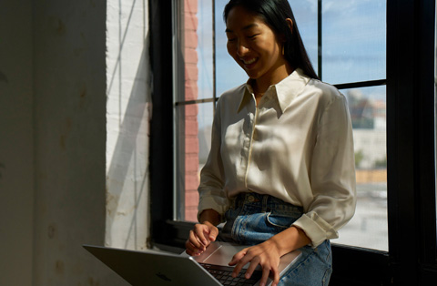 Karyawan Apple Store berdiri di sebelah pelanggan, keduanya berinteraksi dengan MacBook.