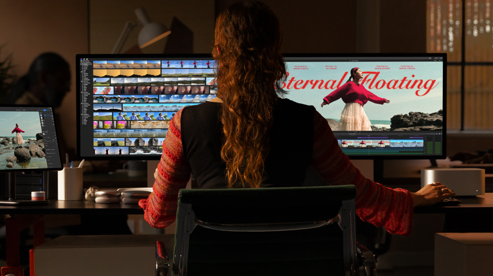 Vista traseira de uma pessoa sentada em frente a dois monitores, que mostram o conteúdo de vídeo a ser editado.