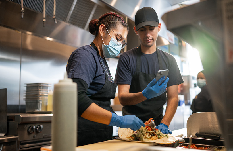 Une employée apprend à rouler un burrito « façon Sisig ».