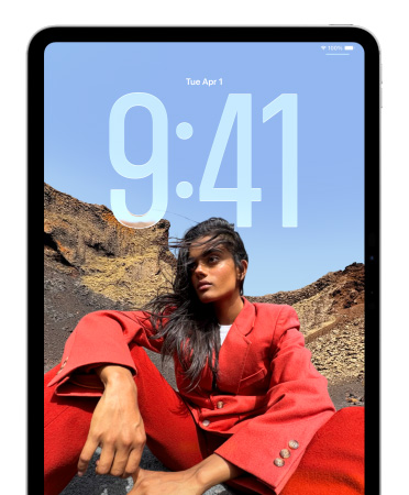 iPad a mostrar o ecrã bloqueado, com os números das horas a aparecer em tamanho grande por trás da fotografia de uma pessoa sentada